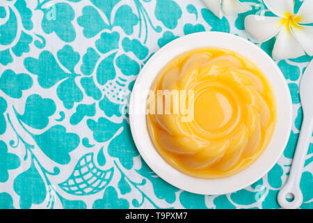 Mango pudding, jelly, dessert on white plate. Colorful textile background. Top view. Copy space. Stock Photo
