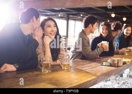 Happy young couple whispering in bar Stock Photo