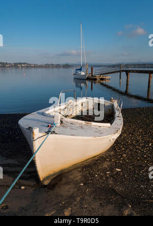 A white fishing dinghy on the shore at George Town on the Tamar River near Launceston in northern Tasmania, Australia. Stock Photo