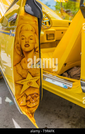 A detail of the back of an open door of a bright yellow Chevrolet lowrider car that has been completely customized including a hand painted portriat o Stock Photo