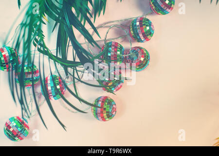 concept image of tropical winter holidays with felt christmas tree palm leaf and illumination lights Stock Photo