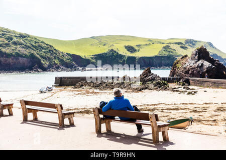 Hope Cove, Devon, UK, England, Hope Cove Devon, Man looking out to sea, sitting on bench, leaning on bench, overlooking sea, enjoying view, relaxing, Stock Photo