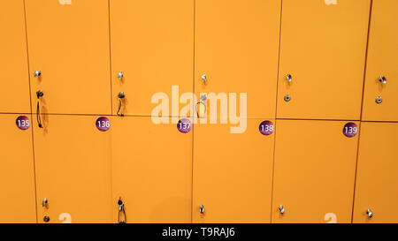 CLoseup image of straight long rows of yellow lockers in the school or college Stock Photo