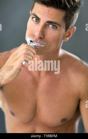 Close up portrait of a young man brushing teeth in the bathroom Stock Photo