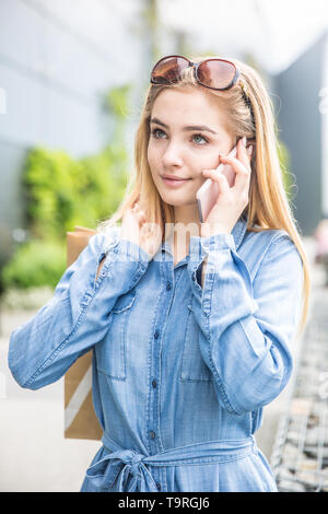 Beautiful young girl calling in shopping mall with baggs. Stock Photo