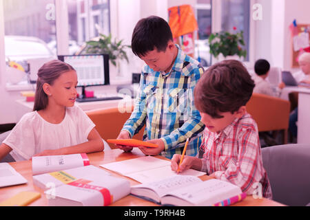 Three pupils working on their homework together. Stock Photo