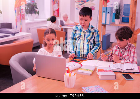 Children using modern technologies doing their homework. Stock Photo