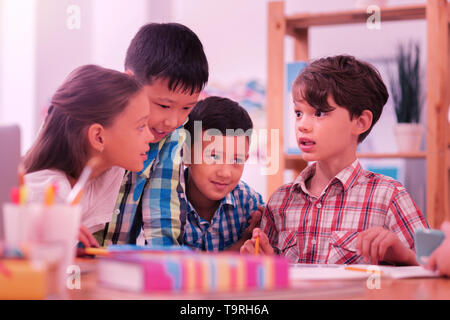 Children at the schooldesk discussing their exercises. Stock Photo