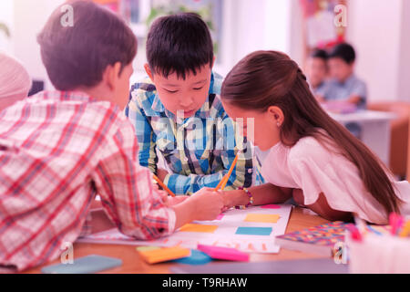 Children working on their school project together. Stock Photo