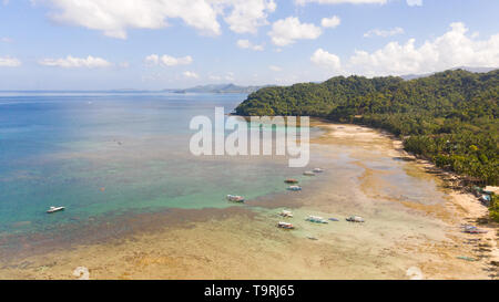 Lagoon with a coral reef and a large island.Seascape with boats and islands, Philippines, aerial view. Stock Photo