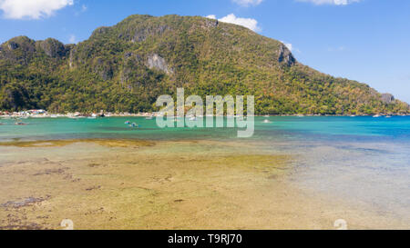 Lagoon with a coral reef and a large island.Seascape with boats and islands, Philippines, aerial view. Stock Photo