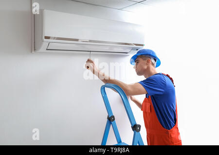 Male technician repairing air conditioner indoors Stock Photo
