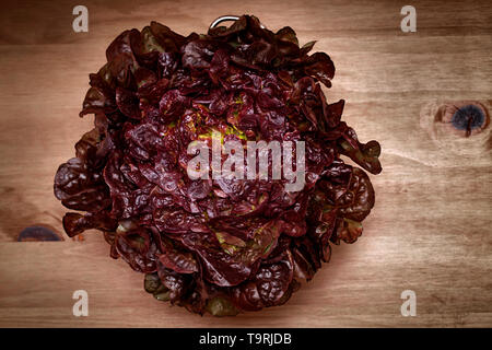 red leaf lettuce in a colander on wood board background Stock Photo