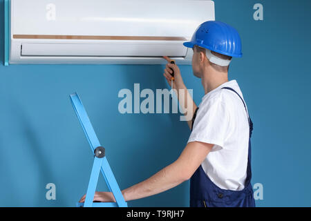 Male technician repairing air conditioner indoors Stock Photo