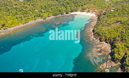 Sea bay with turquoise water and a small white beach.Coast of the island of Camiguin, Philippines.Beautiful lagoon and volcanic island covered with dense forest, view from above. Stock Photo