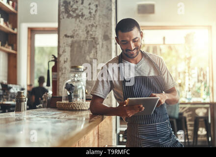 Young african entrepreneur using digital tablet in his cafe Stock Photo