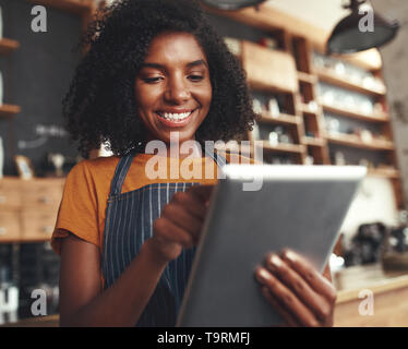 Smiling female cafe owner using digital tablet Stock Photo