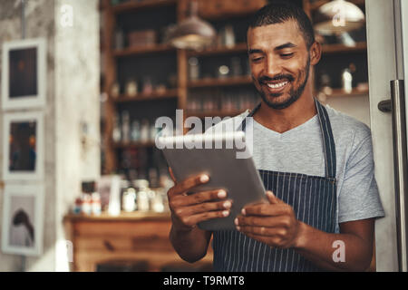 Successful barista cafe owner looking at digital tablet Stock Photo