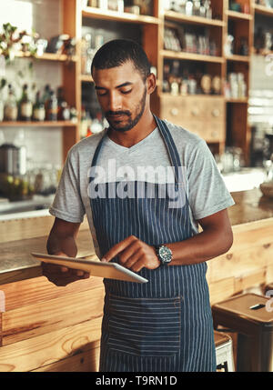 Small business owner at his coffee shop using digital tablet Stock Photo