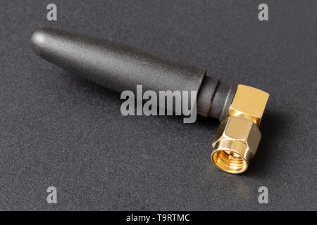 compact Wi-Fi antenna with gold-plated plug on a dark background Stock Photo