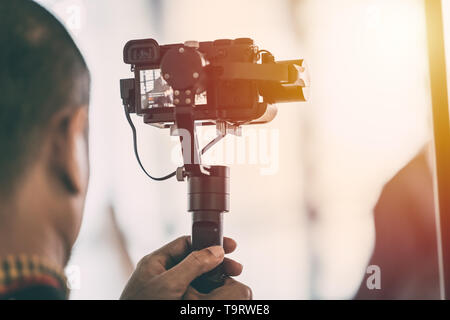 Videographer recording video with mirrorless digital camera on Gimbal Stabilization system Stock Photo