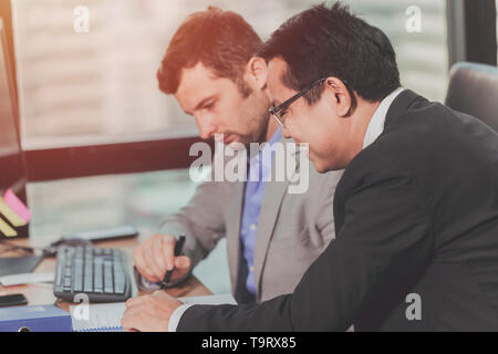two business man talking with partner mix race Asian and Caucasian male, Boss executive working help care with employee in office. Stock Photo