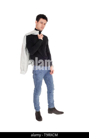 A good looking young man standing in a black sweater and jeans with his jacket over his shoulder, isolated for white background Stock Photo
