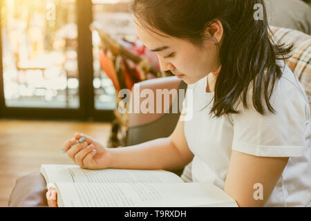 Cute Asian young girl teen doing homework paper warm vintage color tone Stock Photo