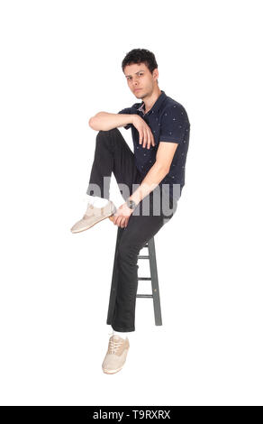 A good looking young man in black clothing sitting on a chair in the studio, resting, isolated for white background Stock Photo