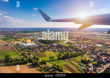 Airplane windows view above the earth on landmark down. View from an airplane window over a wing flying high above farmlands and fields. View from win Stock Photo
