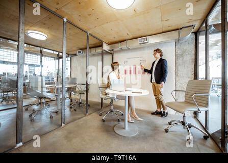 Man showing chart to his female business partner during the small conference in the meeting room Stock Photo