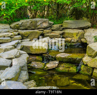 streaming waterfall made out of many rocks, tropical garden architecture Stock Photo