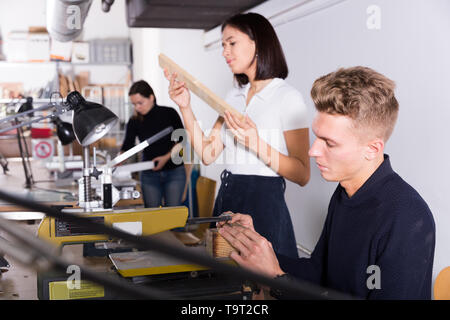 Male student of architecture faculty using scroll saw while engaged in architectural modeling in university workshop Stock Photo