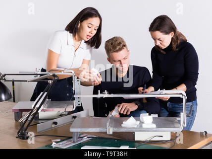 Students and teacher of architecture faculty discussing details of architectural model in university workshop Stock Photo