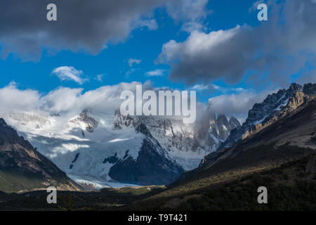 The snow-capped tip of Cerro Torre peeks through the clouds at right.  At lower left is the Grand Glacier.  Los Glaciares National Park near El Chalte Stock Photo