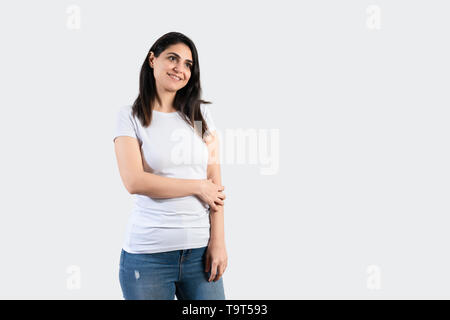 Young girl wearing blank white  t-shirt and blue jeans. Grey wall background . Stock Photo