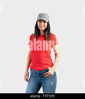Young girl wearing blank red t-shirt, cap  and blue jeans. Grey wall background . Stock Photo