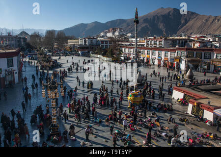 Tibetan pilgrims circumambulate around and prostrate themselves in front of the Jokhang Temple in Barkhor Square in Lhasa, Tibet.  At right are two la Stock Photo