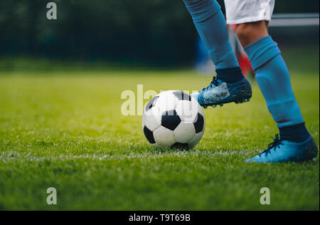 Close up of legs and feet of football player in blue socks and shoes running and dribbling with the ball. Soccer player running after the ball. Sports Stock Photo