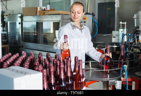 Processing Female Employee A woman employee in a beverage factory scrutinizes bottles on a ...