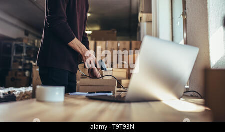 Cropped shot of man scanning the barcode of the shipment at his desk. Man working in a drop shipping office, preparing a parcel to deliver to the cust Stock Photo