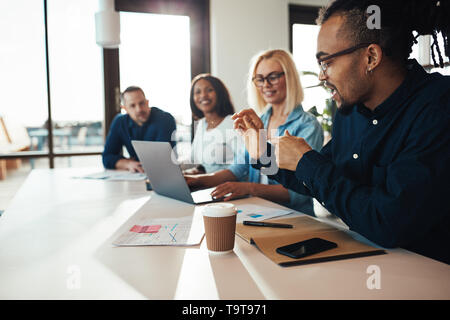 Smiling young African American office worker meeting with a diverse group of colleagues in a modern office Stock Photo