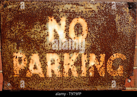 old rusty metal no parking sign on wall Stock Photo