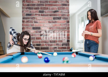 Two female students playing billiard game. Stock Photo