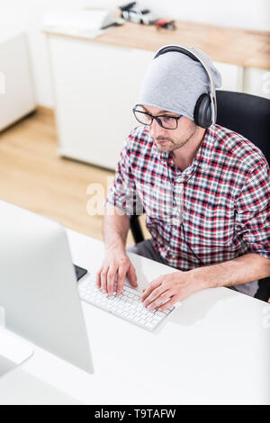 Modern programmer with headphones working on his computer. Stock Photo
