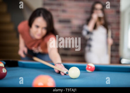 Two female students playing billiard game and drinking beer. Shallow depth of field. Stock Photo