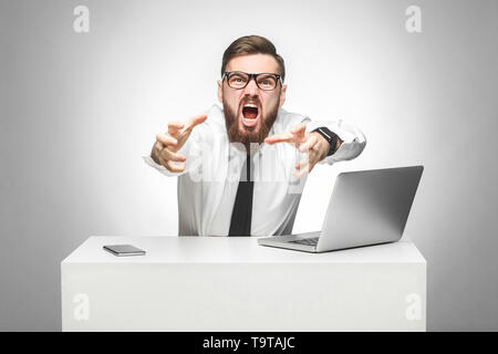 Portrait of aggressive angry young businessman in white shirt and black tie are blaming you in office and having bad mood, screaming and want to stran Stock Photo