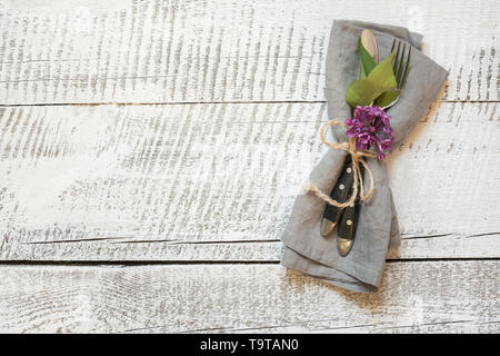 Spring festive table setting with cutlery and lilac flower on white wooden table. Copy space. View from above. Stock Photo