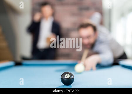 Two fashionable men friends playing billiard game. Shallow depth of field. Stock Photo