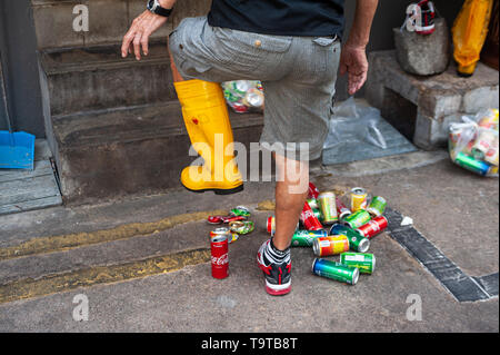 15.03.2019, Singapore, Republic of Singapore, Asia - A man in Chinatown is crushing empty beverage cans with a rubber boot. Stock Photo